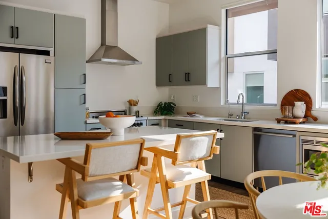 a kitchen with stainless steel appliances granite countertop a sink a stove and chairs