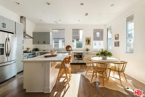 a kitchen with stainless steel appliances a table and chairs in it