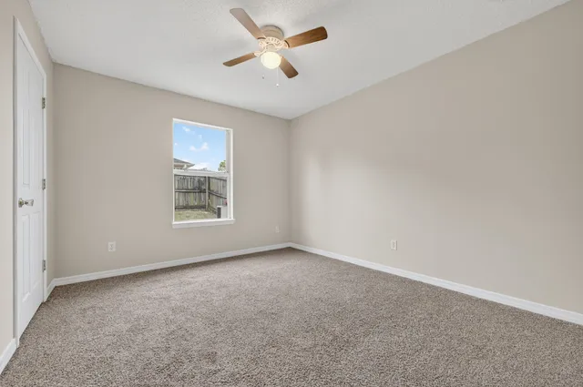 an empty room with a window and a ceiling fan