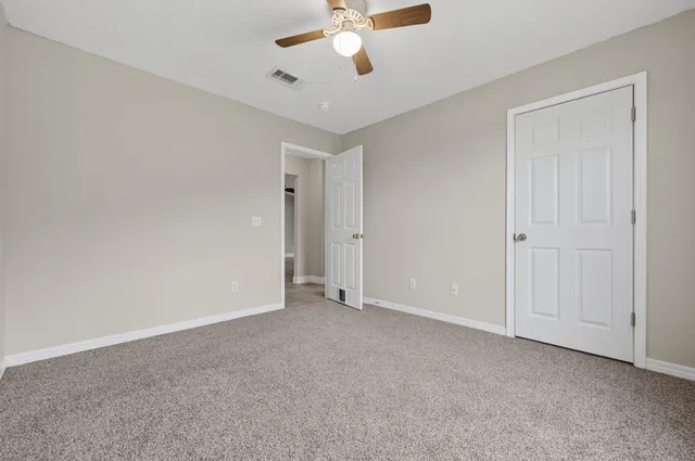 a view of an empty room with a chandelier fan