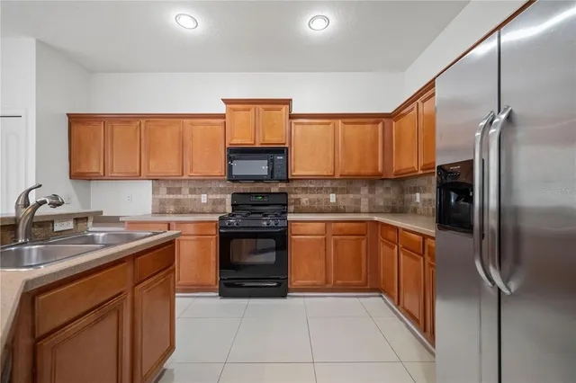 a kitchen with stainless steel appliances granite countertop a sink stove refrigerator and cabinets