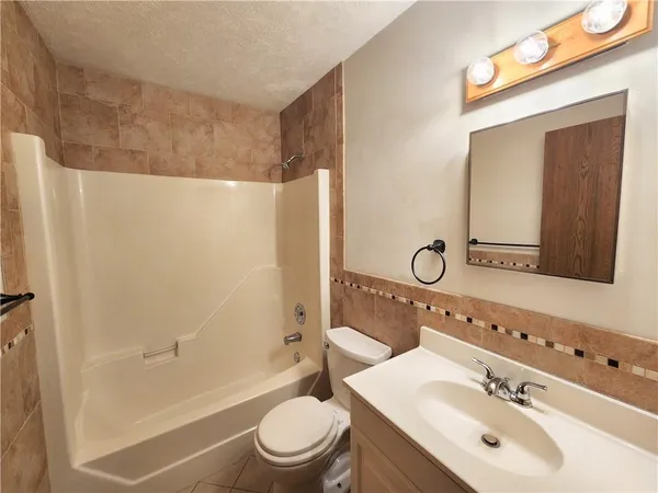 a bathroom with a bathtub shower sink vanity mirror and toilet
