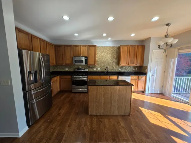 a kitchen with stainless steel appliances granite countertop a refrigerator a sink dishwasher a stove with wooden floor and cabinets