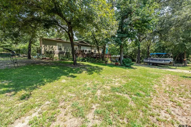 a view of a house with a big yard and large trees