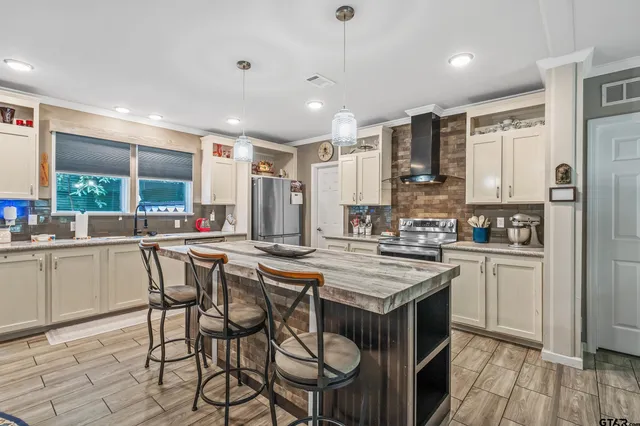 a kitchen with stainless steel appliances granite countertop a stove top oven a sink dishwasher a dining table and chairs with wooden floor