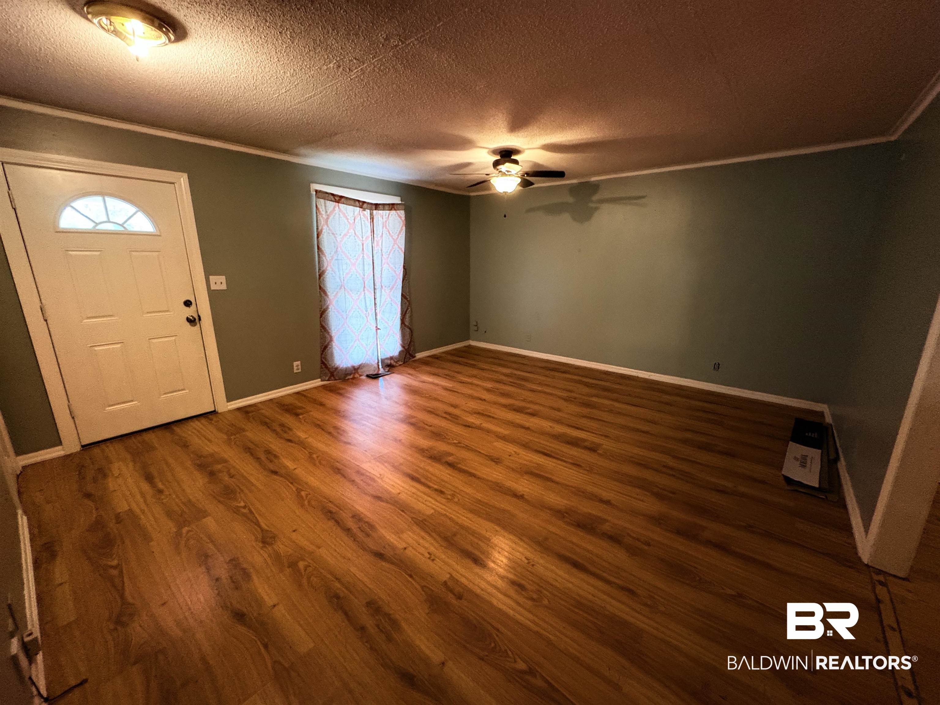 8065 Middle Ring Road Mobile, AL 36619 - Photo 4 of 21 Foyer entrance with crown molding, a ceiling fan, dark wood-style flooring, and a textured ceiling