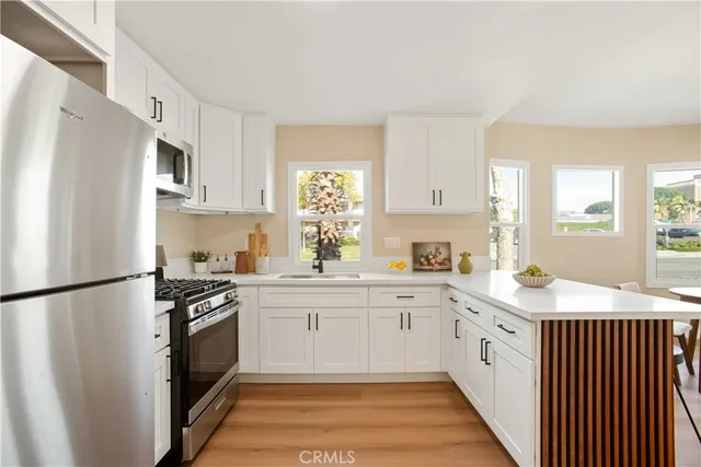a kitchen with white cabinets stainless steel appliances and a window