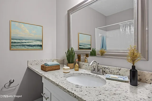 a bathroom with a granite countertop sink a large mirror and a shower