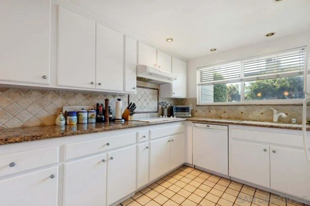a kitchen with white cabinets and window