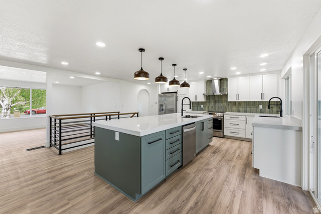 871 Bonita Way Centerville, UT 84014 - Photo 2 of 61 Modern kitchen featuring an expansive island with a white countertop and contrasting cabinetry, complemented by sleek pendant lighting