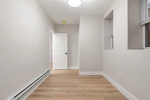 a view of an empty room with wooden floor and a window