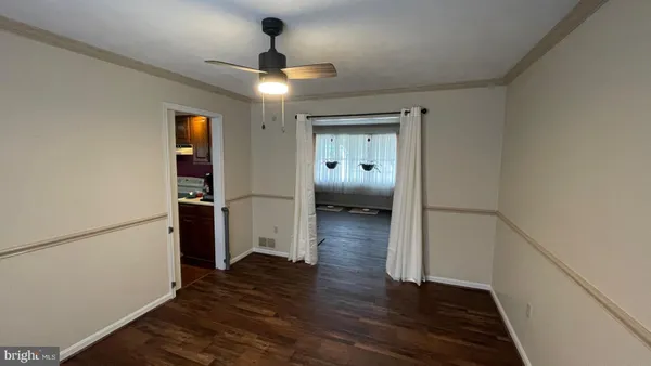 an empty room with chandelier fan and windows