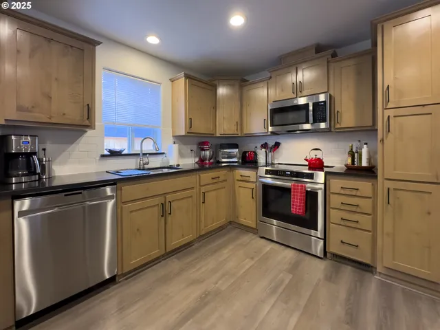 a kitchen with stainless steel appliances granite countertop a stove a sink dishwasher a refrigerator and cabinets with wooden floor