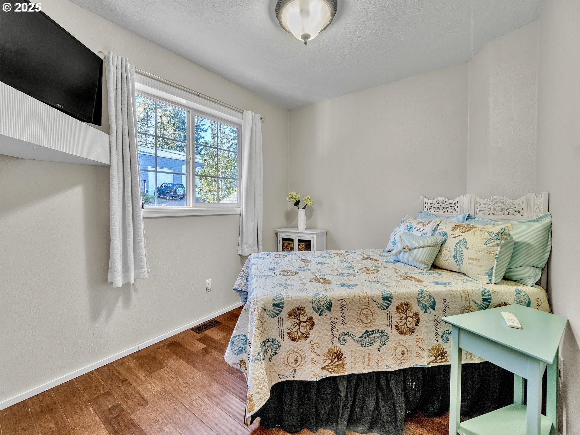 90589 Clark Road Warrenton, OR 97146 - Photo 15 of 48 a bedroom with a bed a window and a flat screen tv