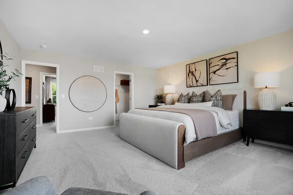 a spacious bedroom with a bed a mirror with dresser and mirror