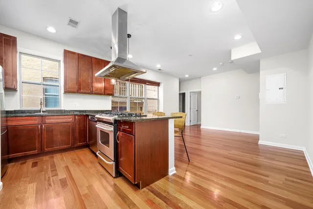 a kitchen with stainless steel appliances granite countertop a sink a stove and a wooden floors