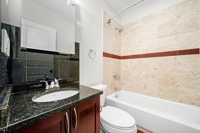a bathroom with a granite countertop sink toilet a mirror and shower