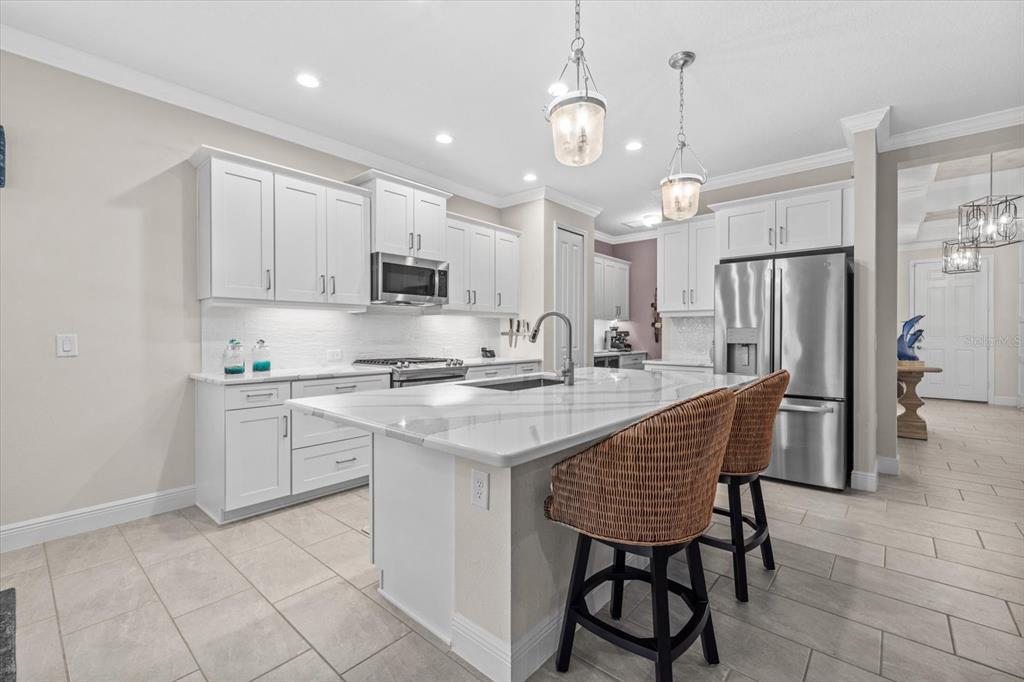 13185 Steinhatchee Loop Venice, FL 34293 - Photo 23 of 50 a kitchen with stainless steel appliances granite countertop a stove a sink dishwasher a refrigerator with a dining table and chairs