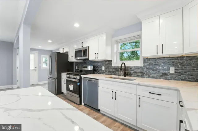 a kitchen with kitchen island granite countertop white cabinets large window and stainless steel appliances