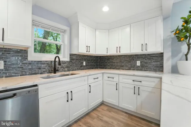 a kitchen with white cabinets and sink