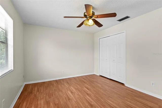 a view of empty room with wooden floor and fan