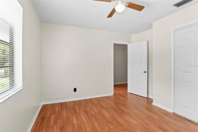 an empty room with wooden floor cabinet and windows