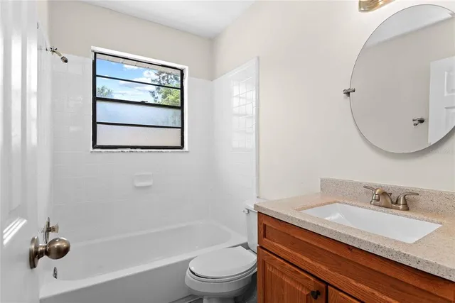 a bathroom with a granite countertop sink toilet a mirror and shower