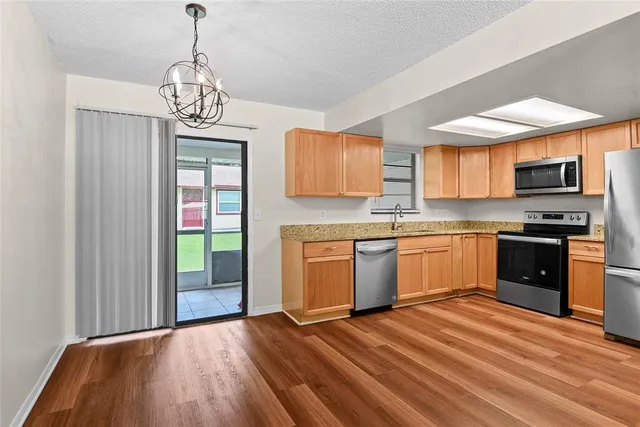 a kitchen with stainless steel appliances granite countertop a stove top oven a sink dishwasher with a microwave oven and refrigerator with wooden floor