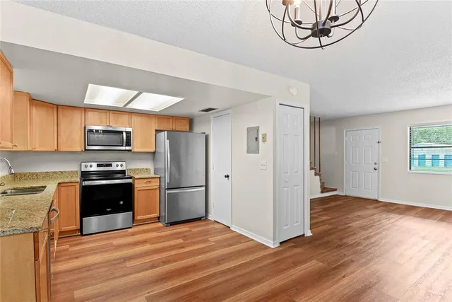 a kitchen with stainless steel appliances granite countertop a refrigerator a stove a sink and a microwave