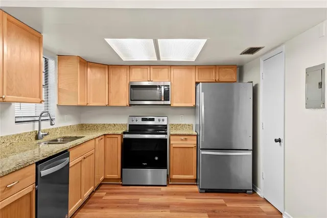 a kitchen with stainless steel appliances granite countertop a refrigerator stove a sink dishwasher and microwave