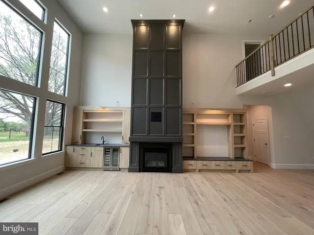 a living room with stainless steel appliances kitchen island granite countertop a refrigerator a oven a cabinets and wooden floors