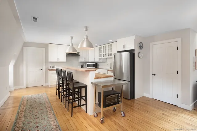 a kitchen with stainless steel appliances a refrigerator a stove a sink dishwasher and white cabinets with wooden floor