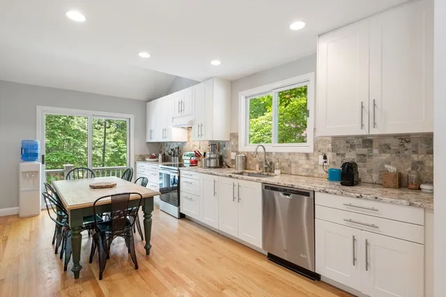 a kitchen with white cabinets a sink dining table and chairs
