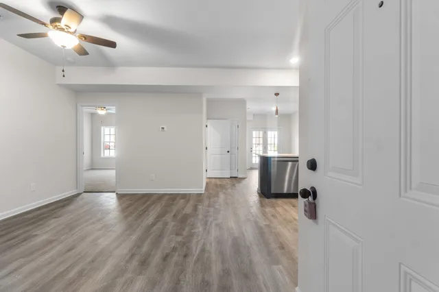 a view of empty room with wooden floor and fan