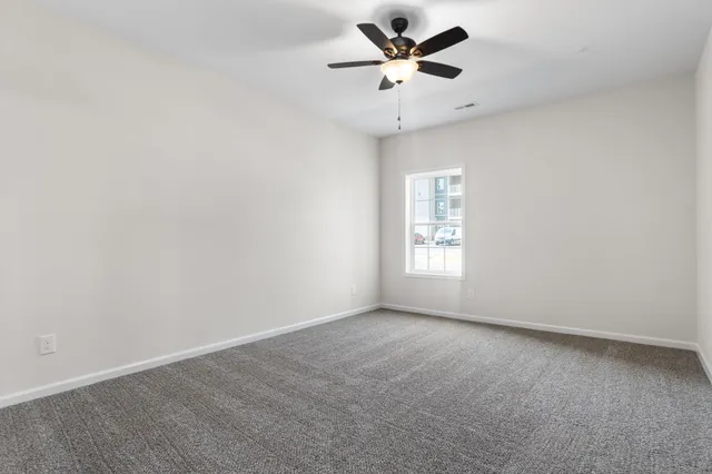 an empty room with a window and a fan