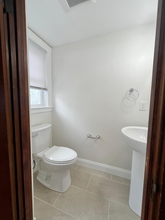 96 Brooks Street, Unit 1 Boston, MA 02135 - Photo 17 of 19 a white toilet sitting next to a bathroom sink and vanity
