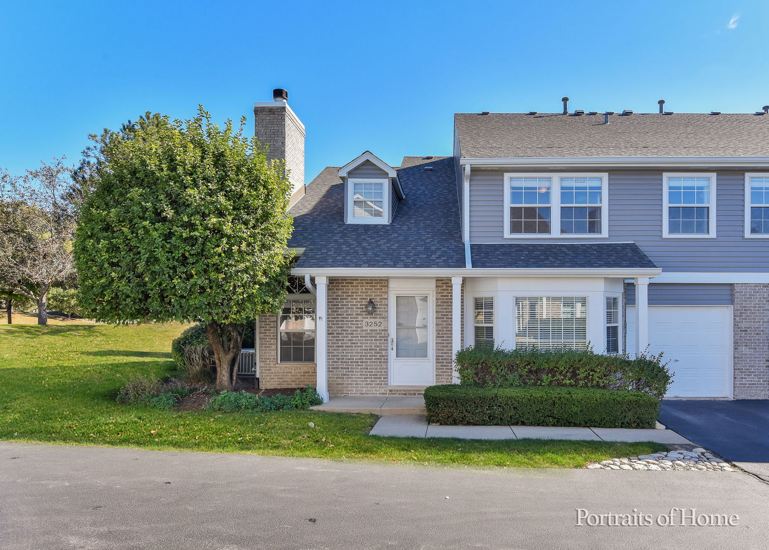 a view of a brick house next to a yard with big trees
