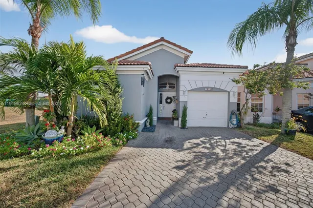 a view of a house with a yard and palm trees