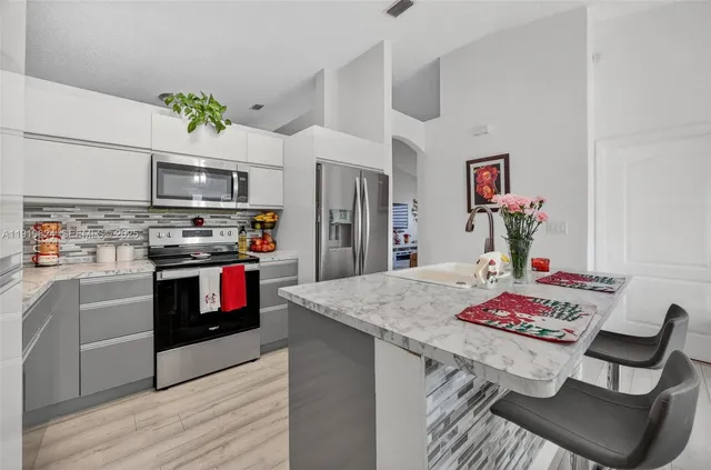 a open kitchen with stainless steel appliances granite countertop a stove refrigerator and a fireplace