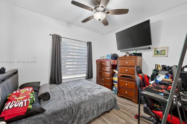 a bedroom with furniture a flat screen tv and a ceiling fan