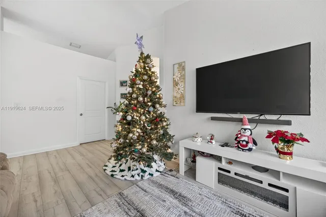 a living room with a flat screen tv and a christmas tree