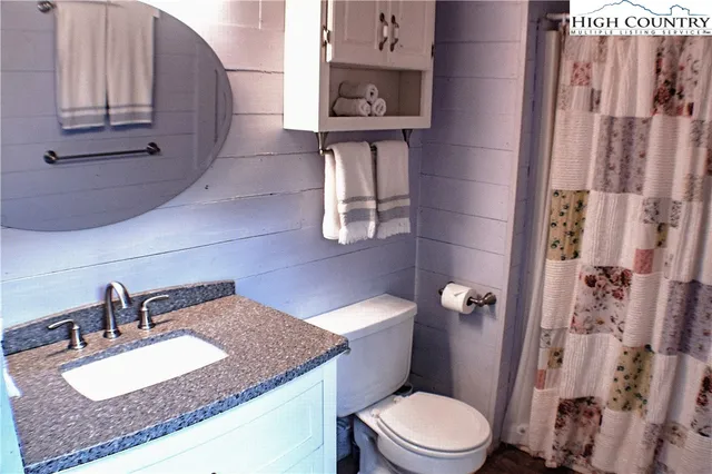 a bathroom with a granite countertop sink a toilet and shower