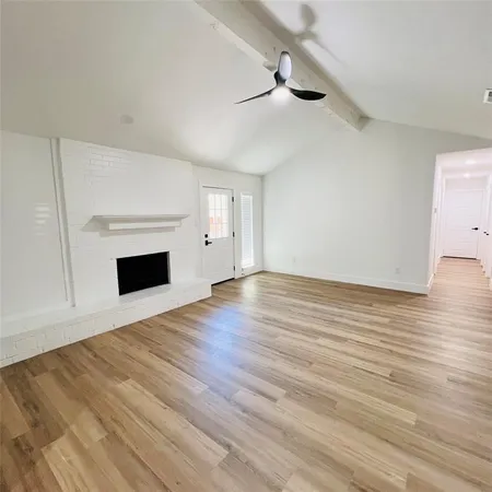 a view of empty room with wooden floor and fireplace