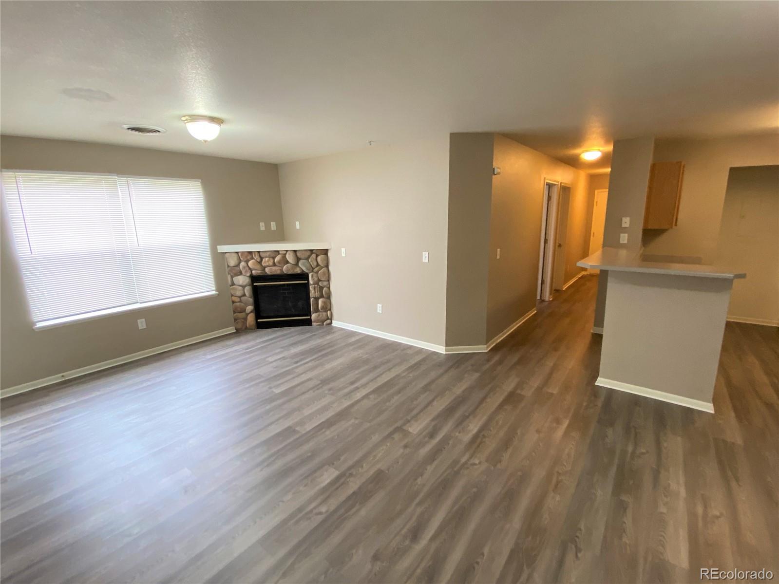 2226 West Elizabeth Street, Unit 202 Fort Collins, CO 80521 - Photo 3 of 9 an empty room with wooden floor a fireplace and windows