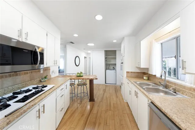 a kitchen with stainless steel appliances granite countertop a stove a sink and a microwave
