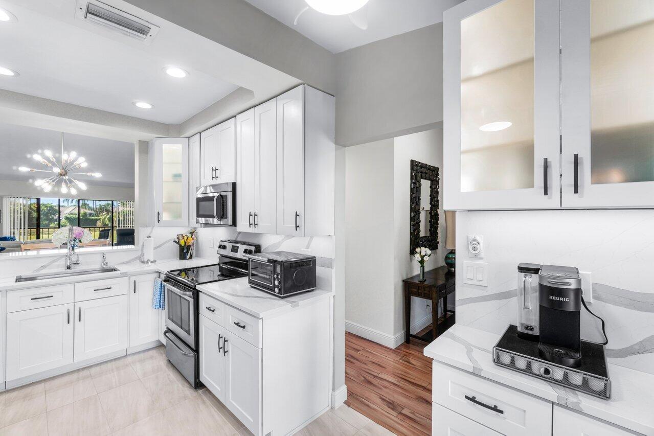 5120 Golfview Court, Unit 1722 Delray Beach, FL 33484 - Photo 2 of 46 a kitchen with white cabinets and appliances