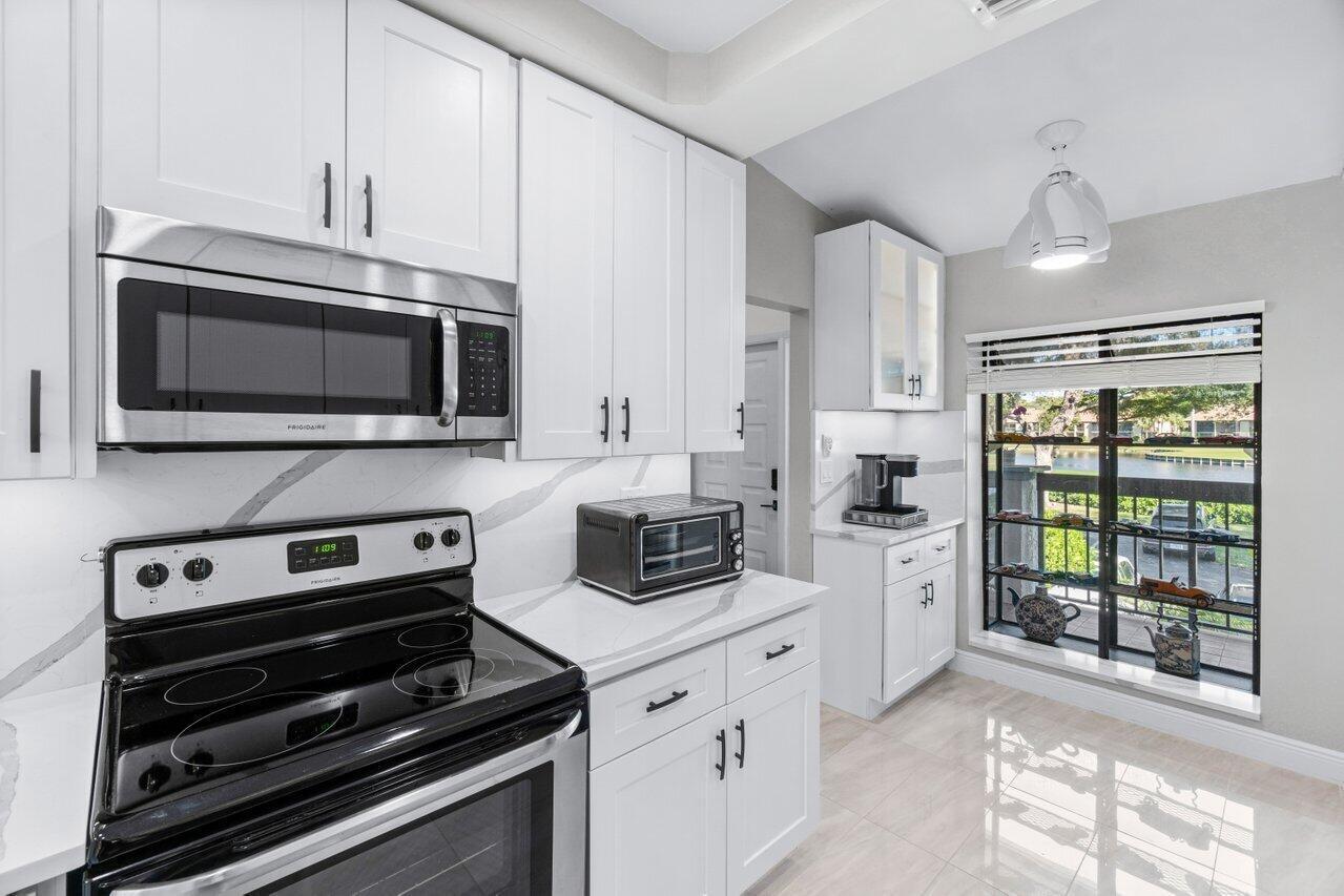 5120 Golfview Court, Unit 1722 Delray Beach, FL 33484 - Photo 6 of 46 a kitchen with stainless steel appliances a stove microwave and refrigerator