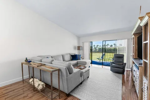 a living room with furniture a flat screen tv and a floor to ceiling window