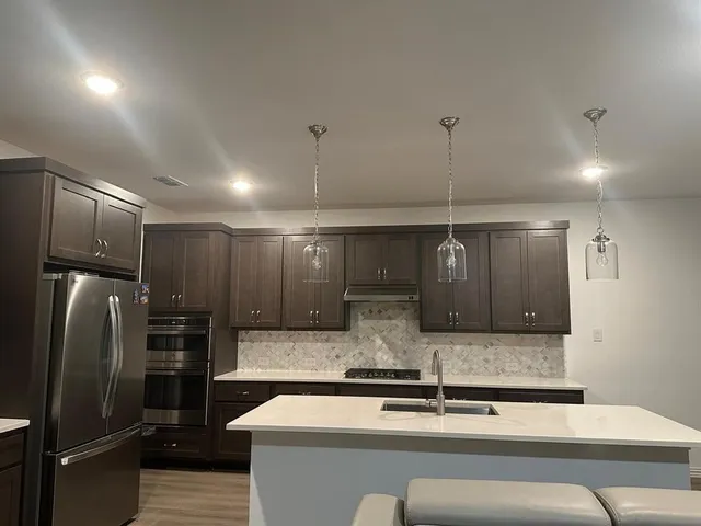 a kitchen with stainless steel appliances kitchen island granite countertop a refrigerator and a counter top