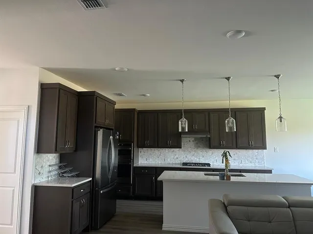 a kitchen with stainless steel appliances kitchen island granite countertop a refrigerator and a stove top oven